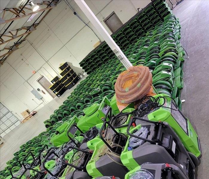 Many pieces of Green SERVPRO Water restoration equipment lined up in a warehouse ready for dispatch 