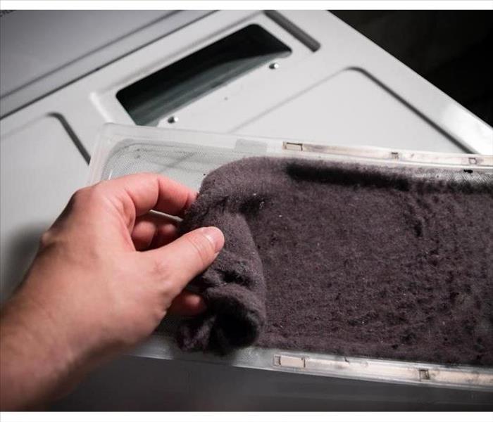 hand removing lint from dryer filter